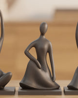 Three abstract human figure sculptures in matte finish, displayed together on a white surface