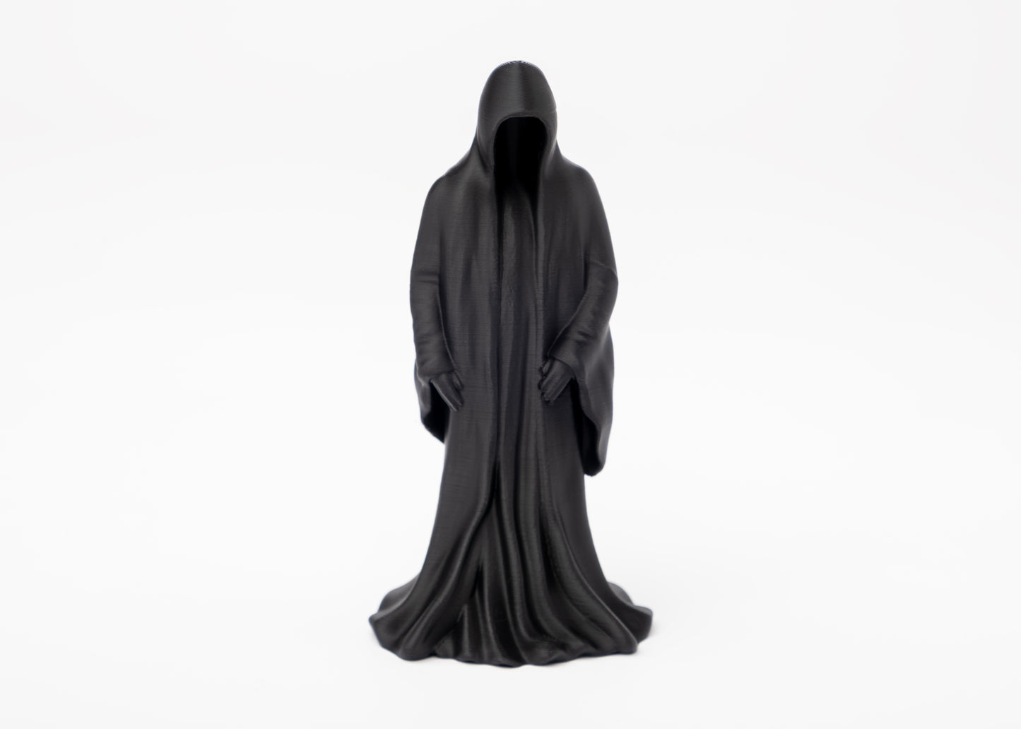 Gothic reaper figure styled on a dark wooden shelf beside a candle and dried botanicals
