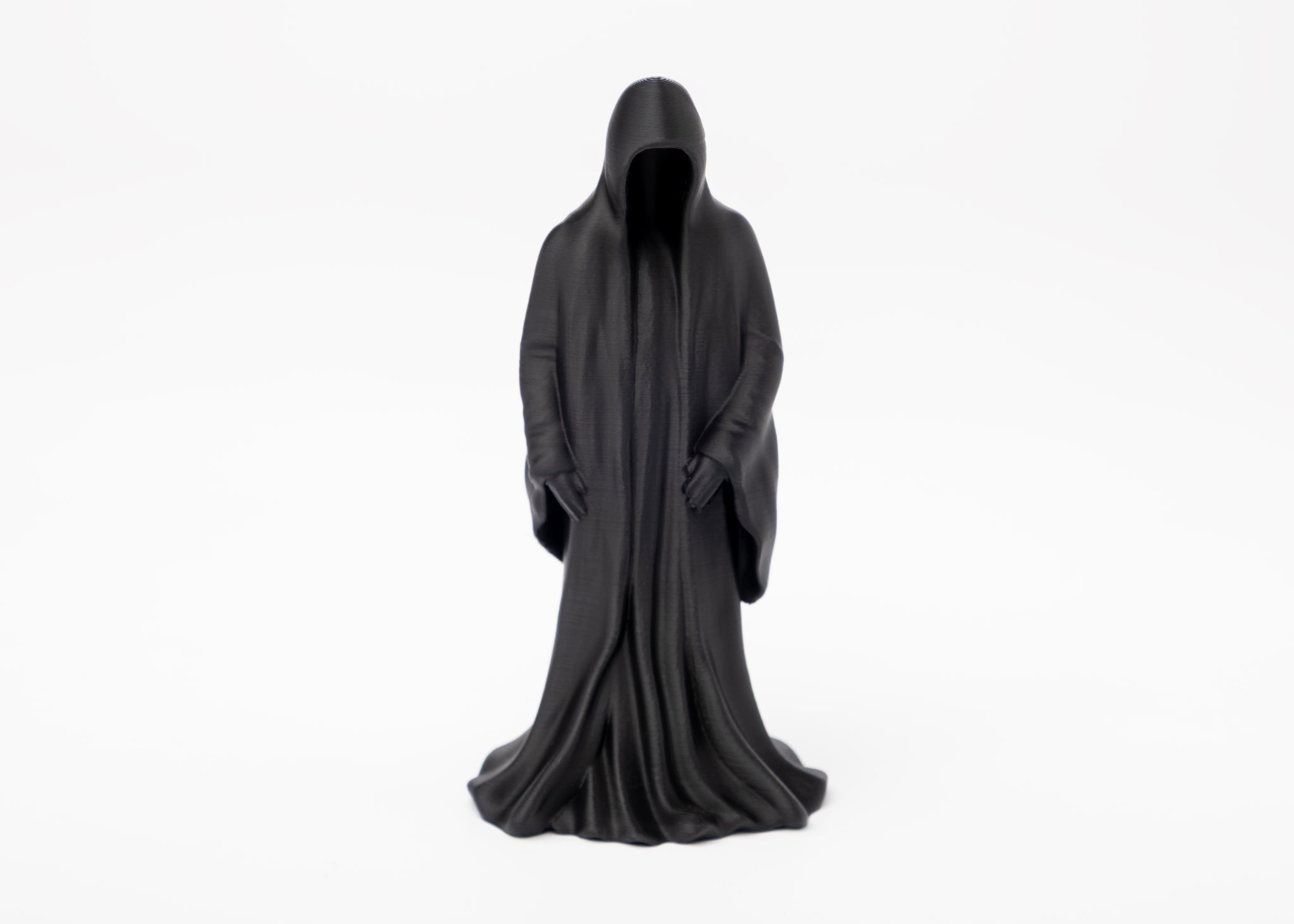 Gothic reaper figure styled on a dark wooden shelf beside a candle and dried botanicals