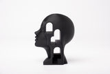 Surreal architectural bust sculpture styled on a minimalist bookshelf with natural decor objects