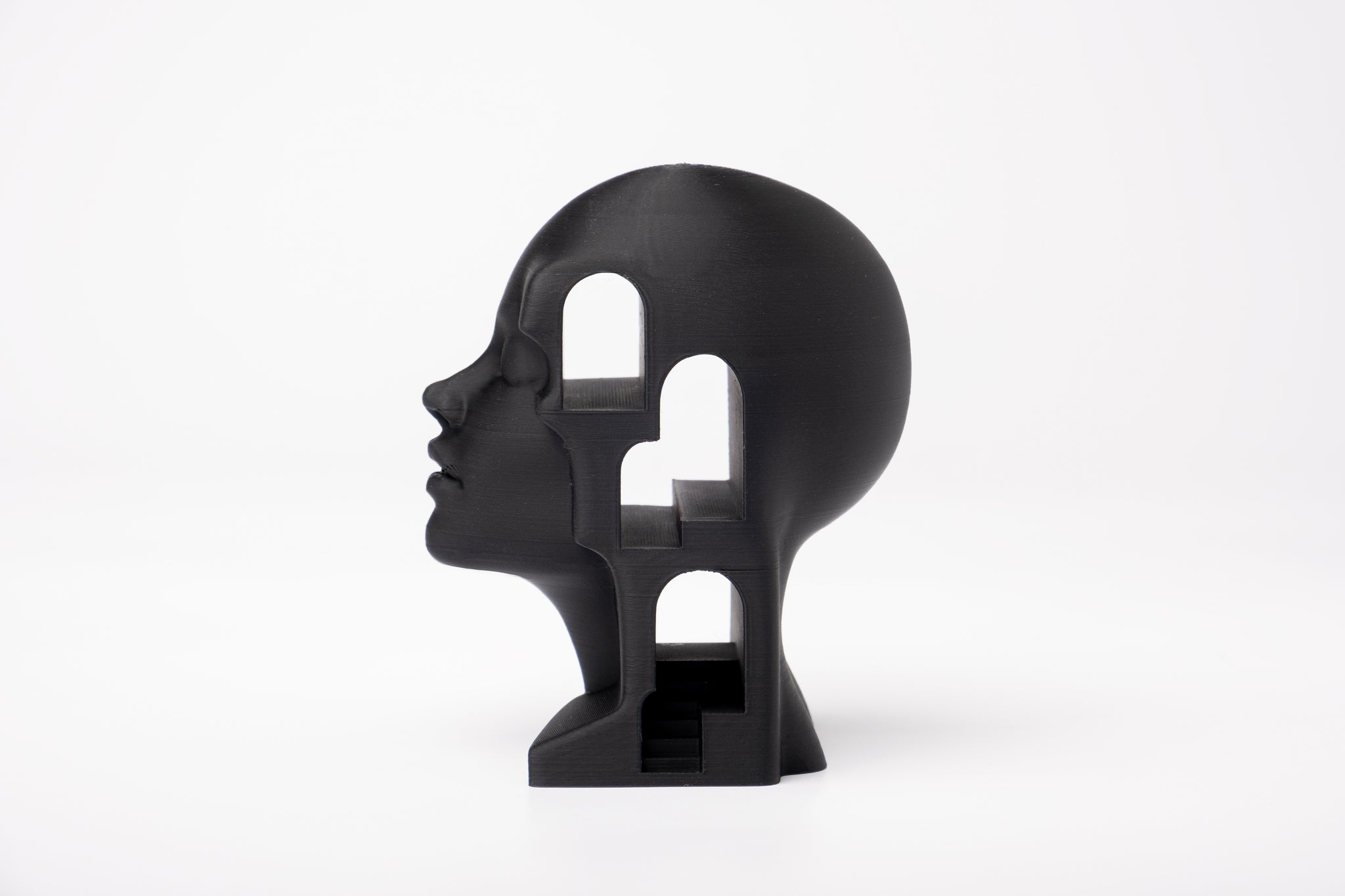 Surreal architectural bust sculpture styled on a minimalist bookshelf with natural decor objects