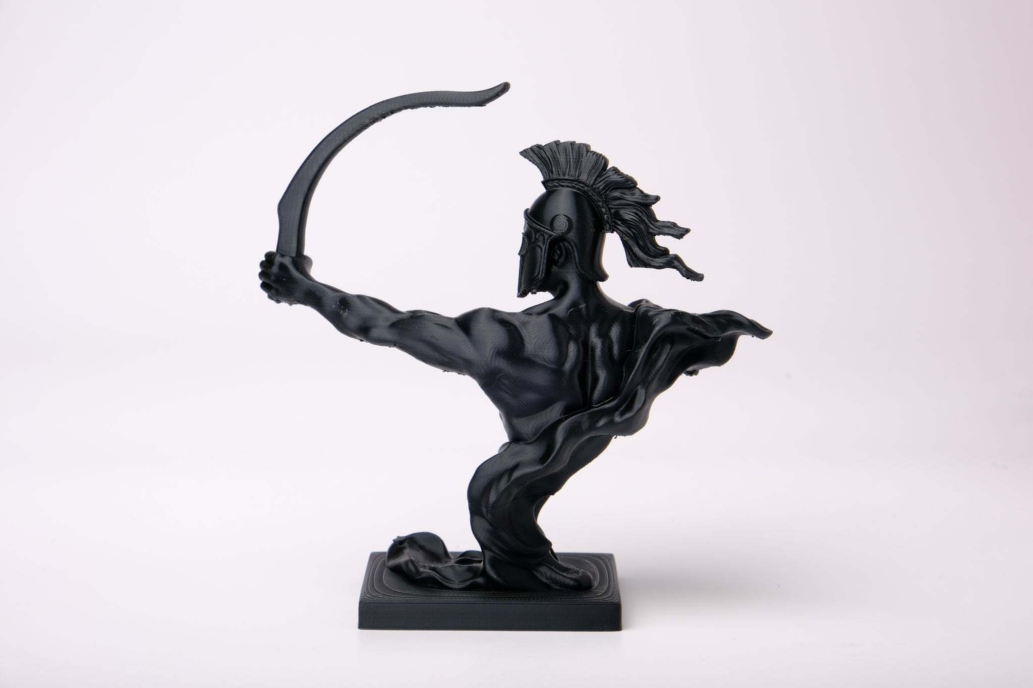 Spartan warrior sculpture displayed on a wooden shelf alongside books and natural decor