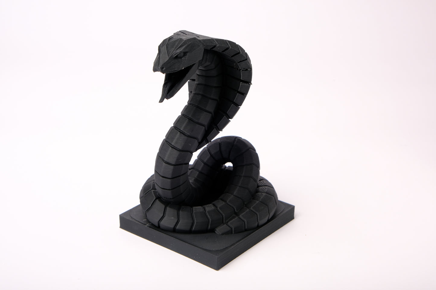 Cobra sculpture displayed on a dark wood desk alongside minimal decor objects