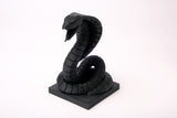 Cobra sculpture displayed on a dark wood desk alongside minimal decor objects