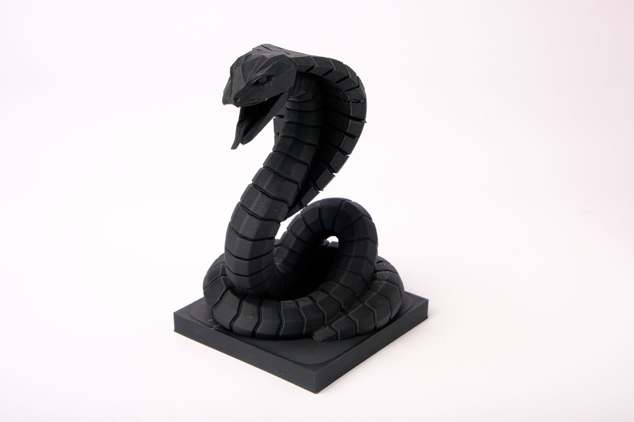 Cobra sculpture displayed on a dark wood desk alongside minimal decor objects