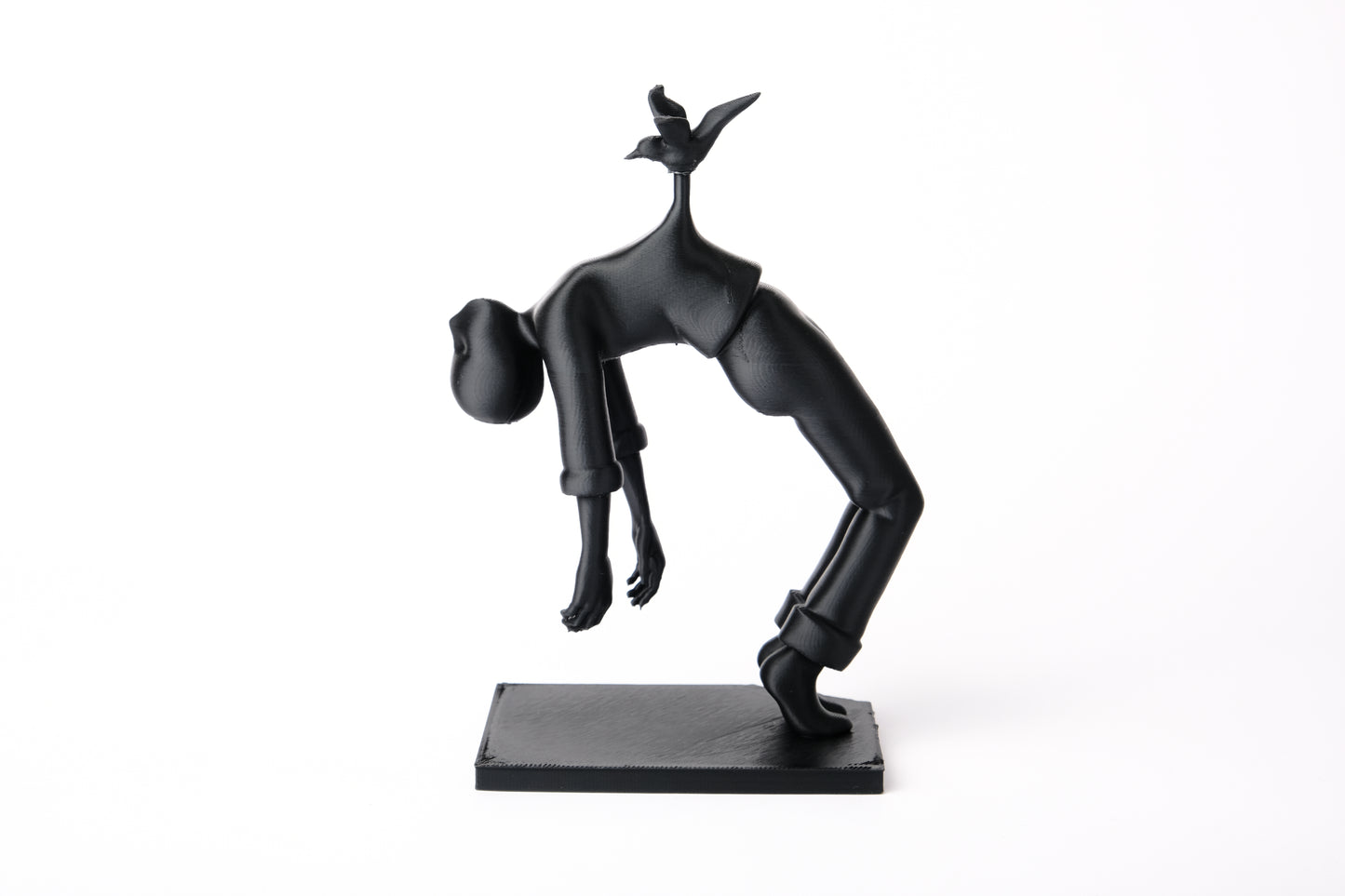 Bird of Burden sculpture styled on a minimal wooden shelf beside books and a small ceramic vessel