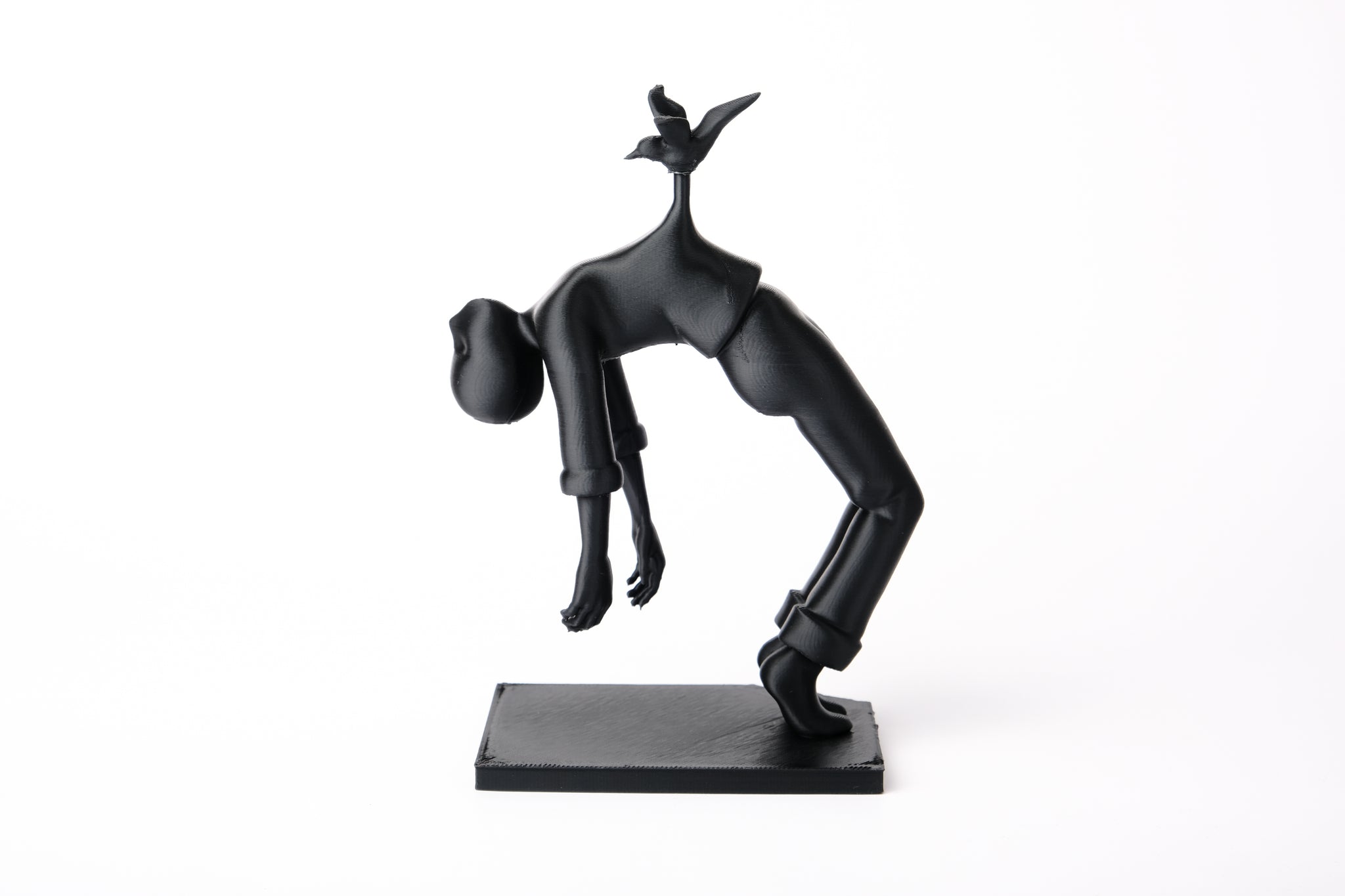 Bird of Burden sculpture styled on a minimal wooden shelf beside books and a small ceramic vessel