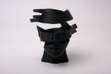Surreal abstract face sculpture styled on a minimalist shelf with books and plants