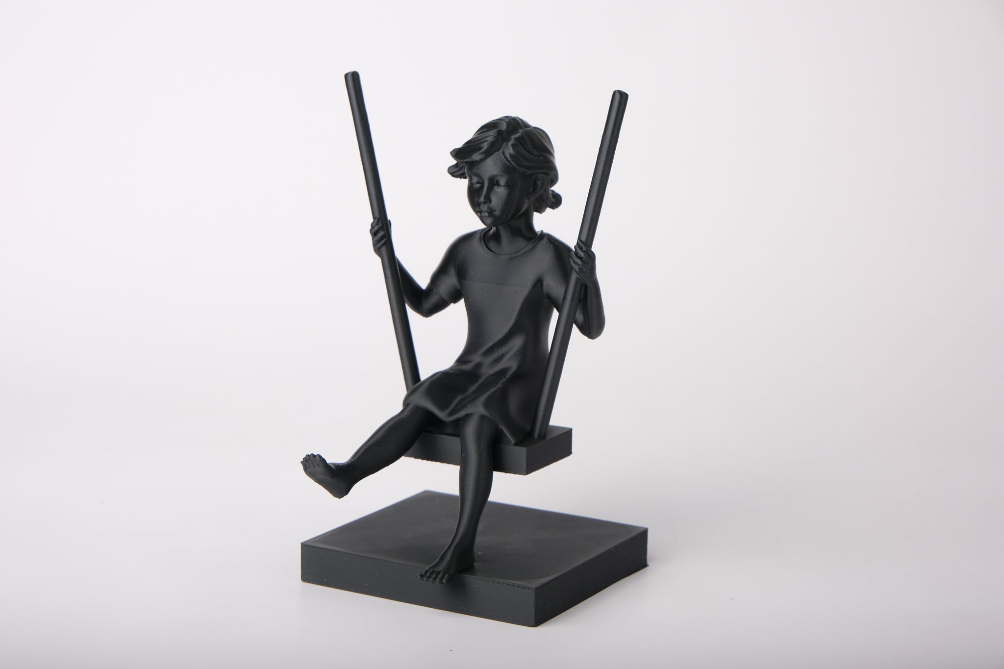 Girl on a swing sculpture styled on a wooden shelf with neutral Scandinavian decor