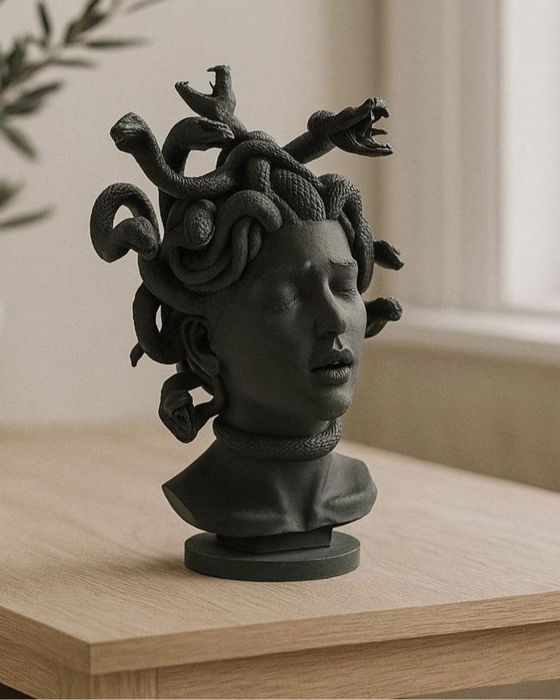 Medusa bust sculpture with closed eyes and detailed snake hair against a neutral background