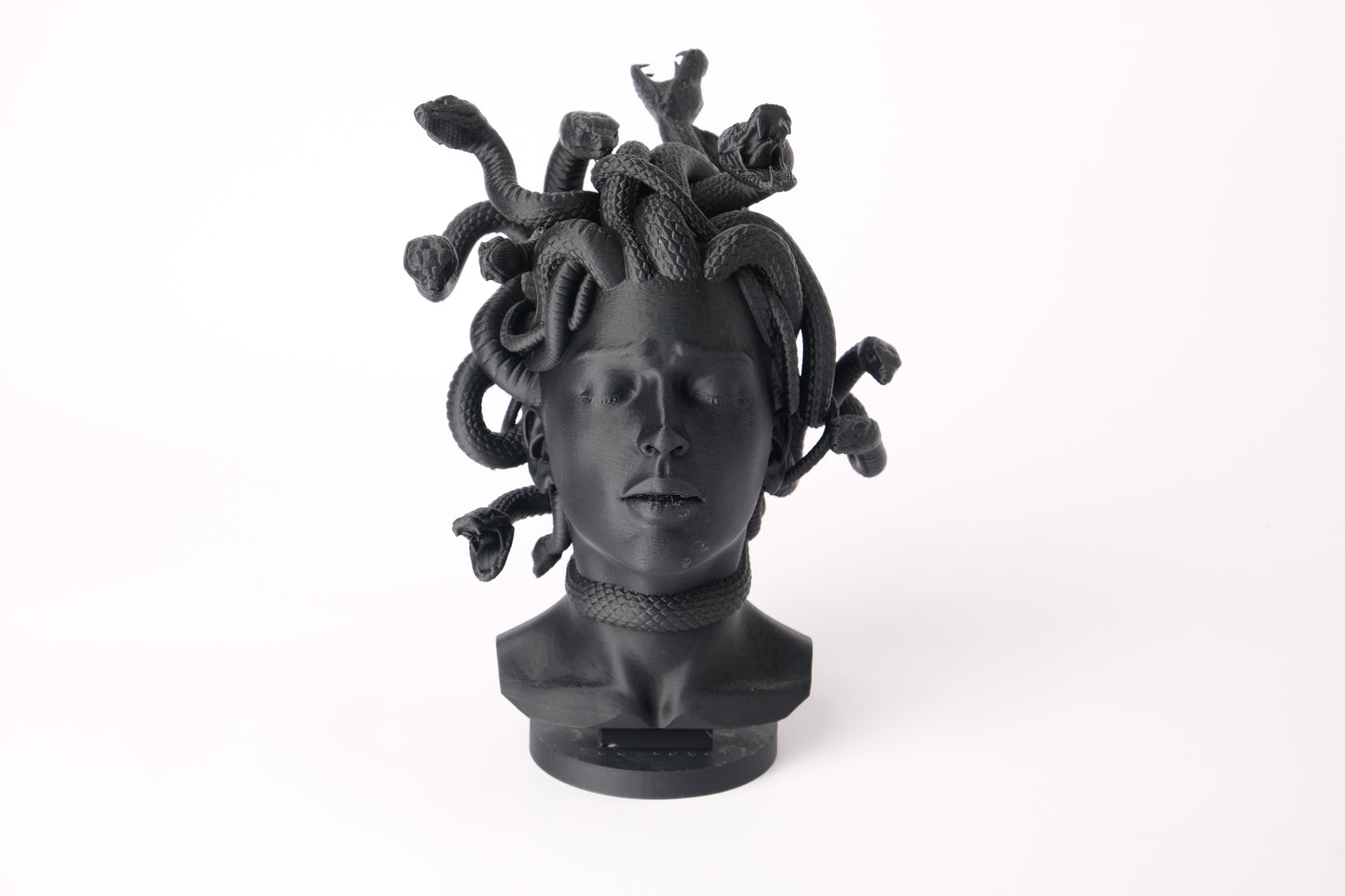 Medusa bust sculpture displayed on a dark wood shelf in a minimalist interior setting