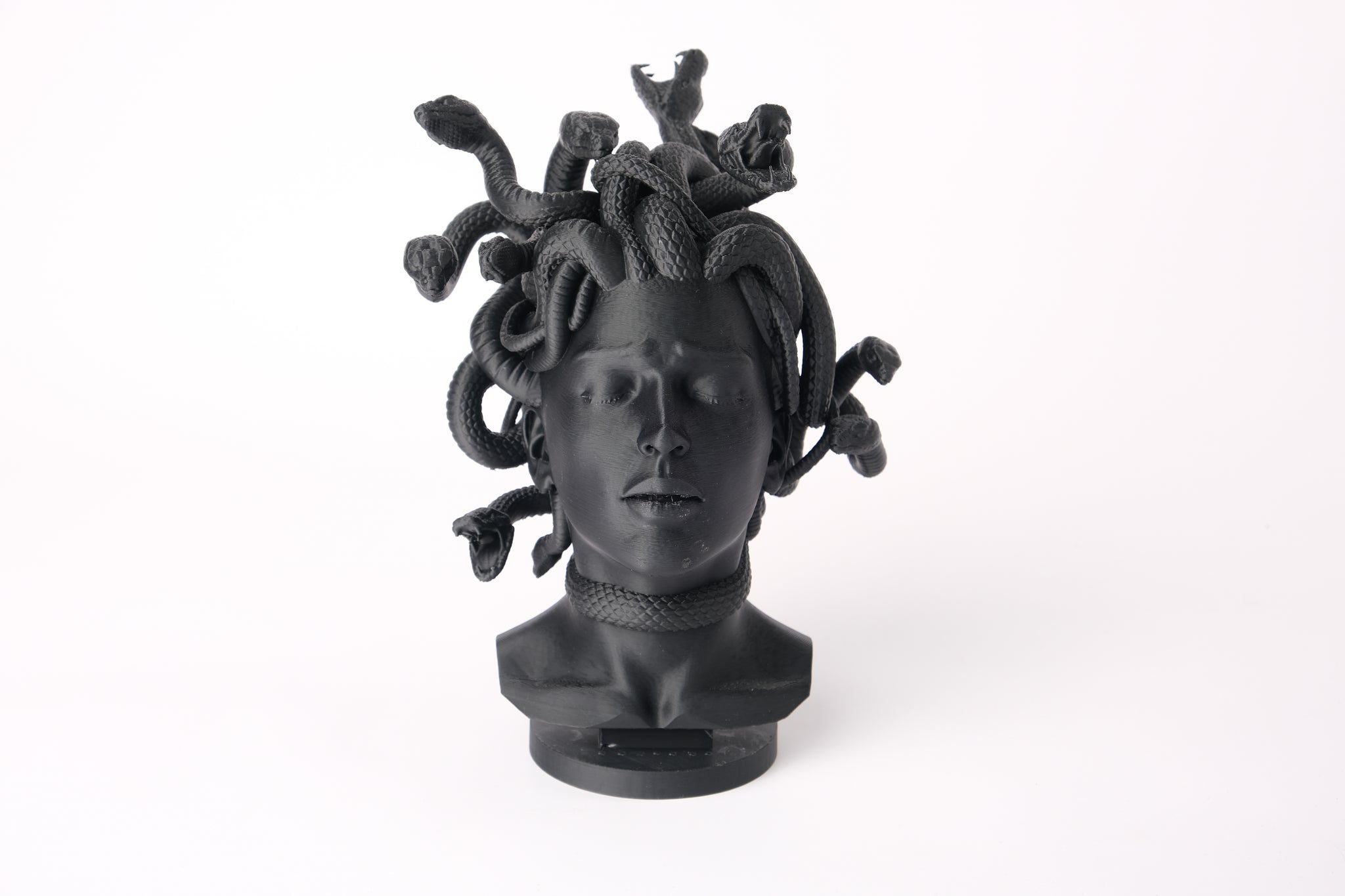 Medusa bust sculpture displayed on a dark wood shelf in a minimalist interior setting