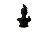 Woman and birds bust sculpture styled on a minimal shelf with books and a dried plant