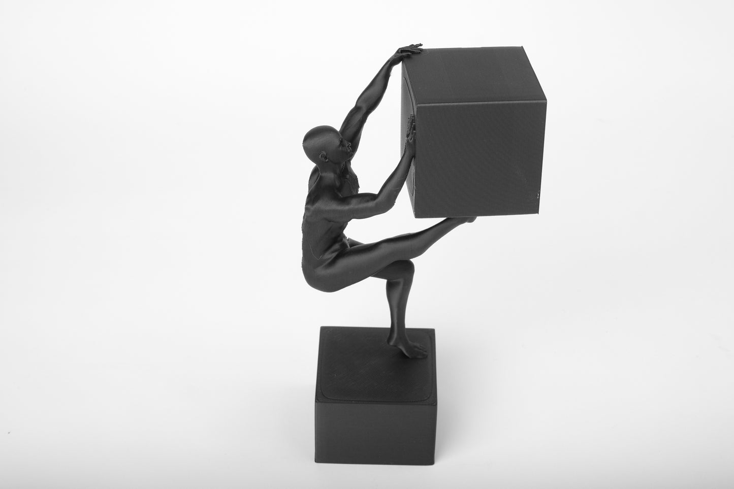 Abstract human sculpture styled on a wooden desk beside books and a ceramic mug in a minimal interior