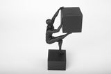Abstract human sculpture styled on a wooden desk beside books and a ceramic mug in a minimal interior