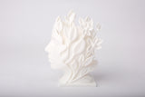 Nature Muse botanical face sculpture styled on a minimalist shelf with ceramics and dried stems