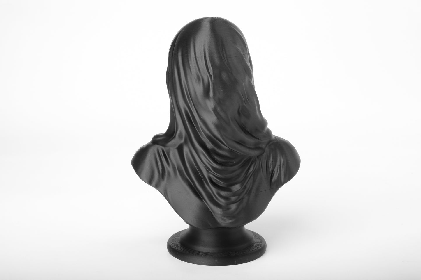 Veiled black bust sculpture styled on a dark shelf alongside candles and dried botanicals