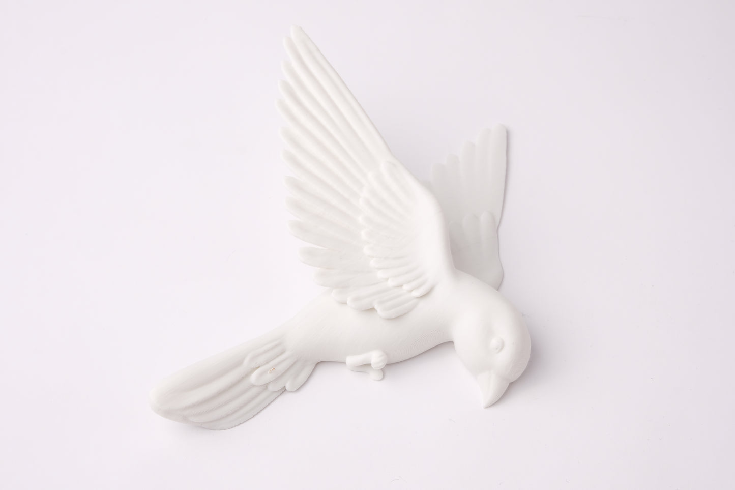 Minimalist white bird wall sculpture arranged on a warm grey living room wall
