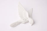 Minimalist white bird wall sculpture arranged on a warm grey living room wall