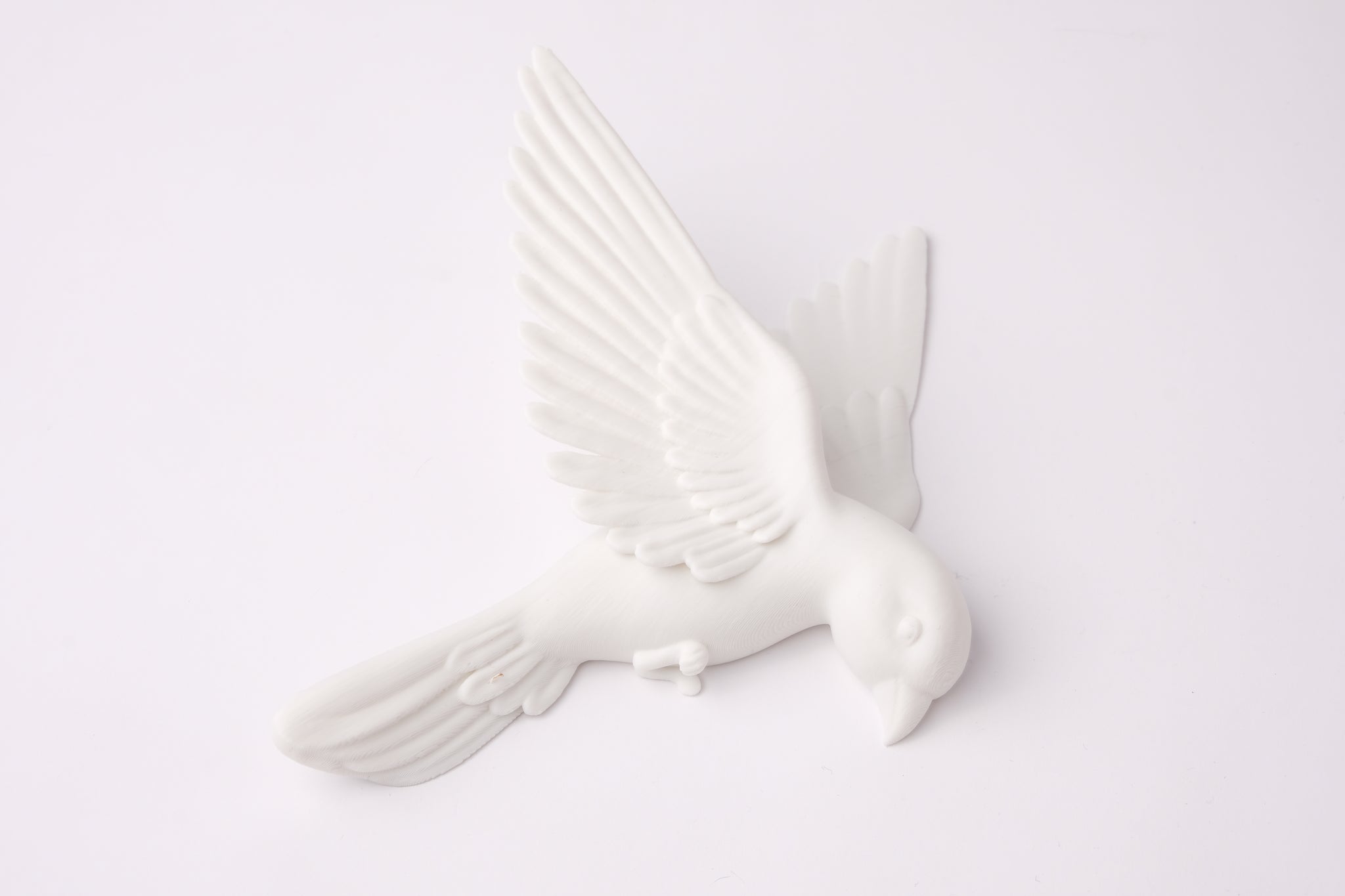Minimalist white bird wall sculpture arranged on a warm grey living room wall