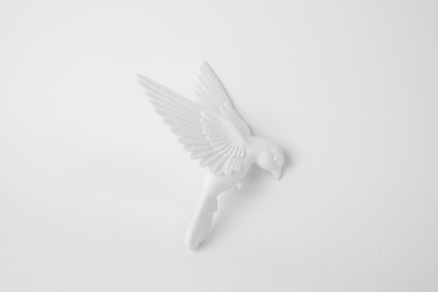 Close-up detail of matte white bird sculpture showing wing texture and clean form