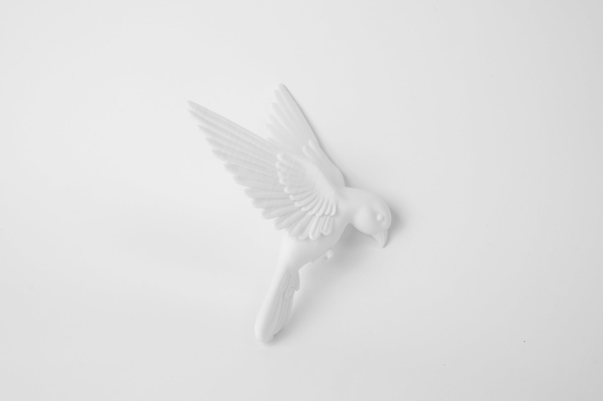 Close-up detail of matte white bird sculpture showing wing texture and clean form