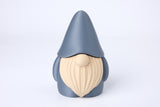 Gnome figurine styled on a bookshelf beside a candle and small plant in a warm, hygge-inspired interior