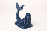 Ethereal mermaid figure styled on a wooden shelf beside coastal home decor