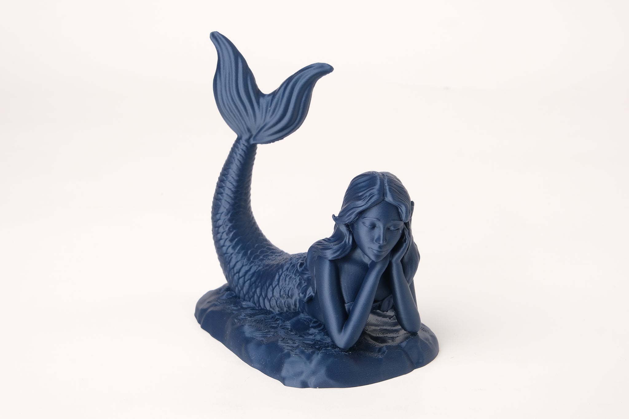 Ethereal mermaid figure styled on a wooden shelf beside coastal home decor