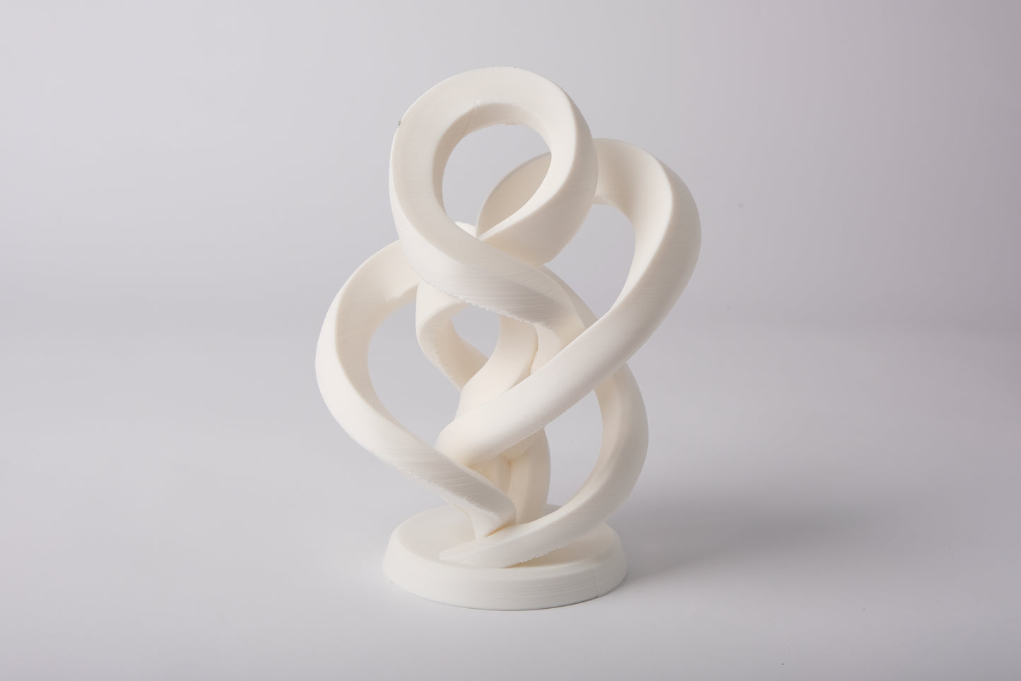 Minimalist abstract infinity sculpture styled on a light wood shelf with neutral decor