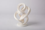 Minimalist abstract infinity sculpture styled on a light wood shelf with neutral decor