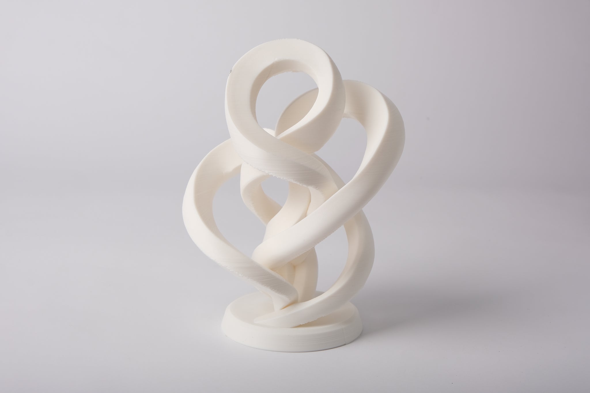 Minimalist abstract infinity sculpture styled on a light wood shelf with neutral decor