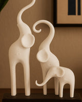 Minimalist elephant sculpture — three stylized figures on a dark base, white background, close-up view