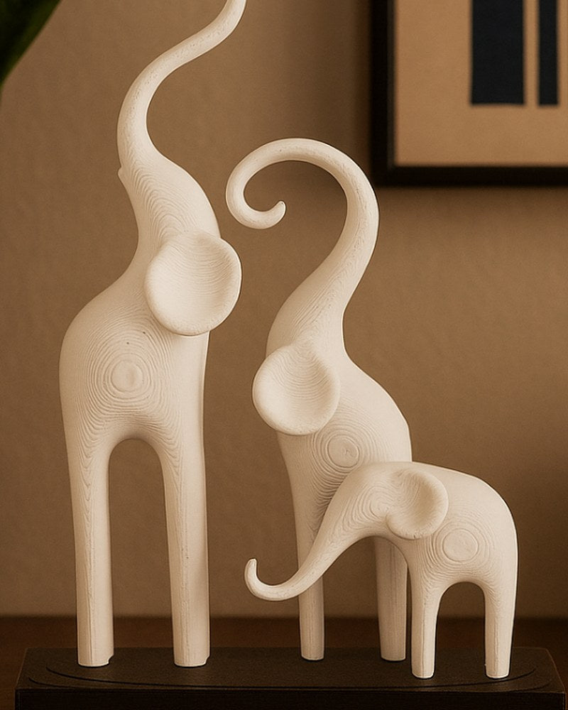 Minimalist elephant sculpture — three stylized figures on a dark base, white background, close-up view