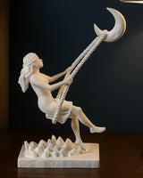 Moon swing sculpture showing a girl figurine perched on a crescent moon, front view on white background