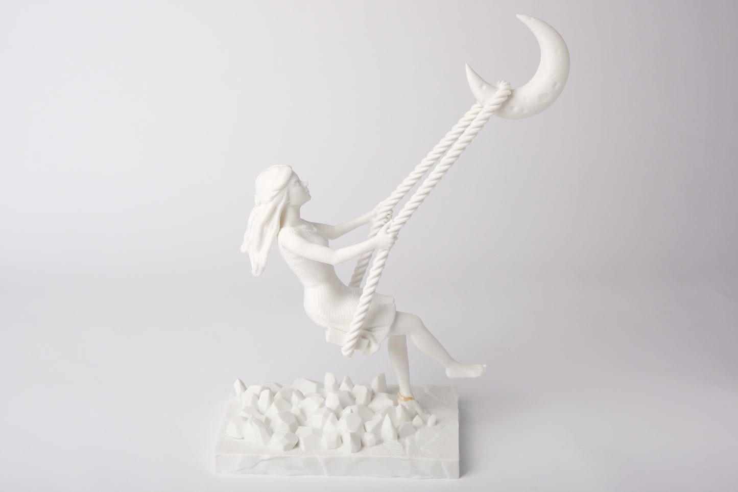 Moon swing sculpture styled on a bedroom nightstand beside a candle and dried flowers