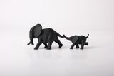 Elephant duo sculpture styled on a wooden shelf next to a small plant and neutral ceramic vase