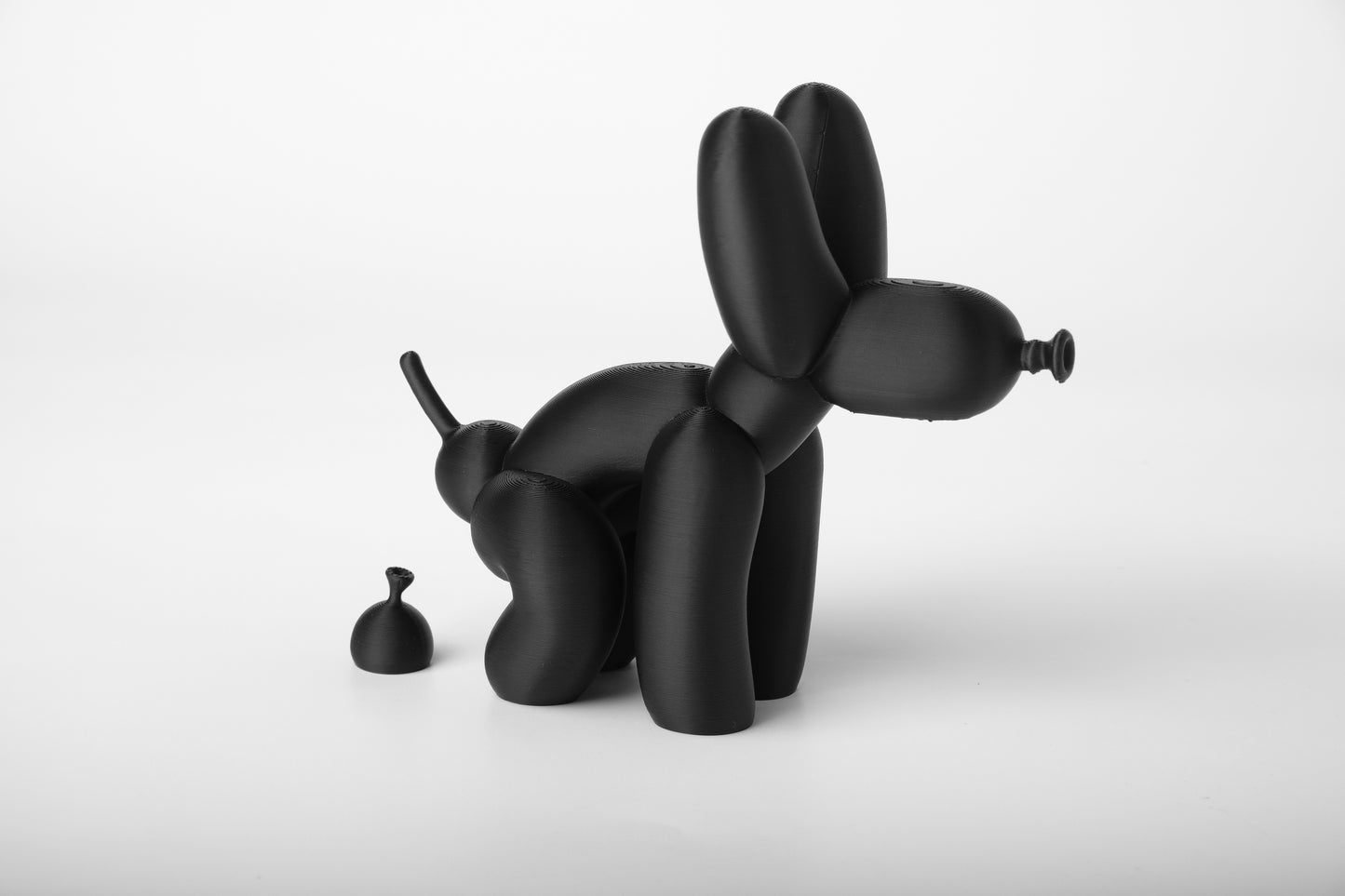 Balloon dog sculpture styled on a wooden shelf next to books and small objects