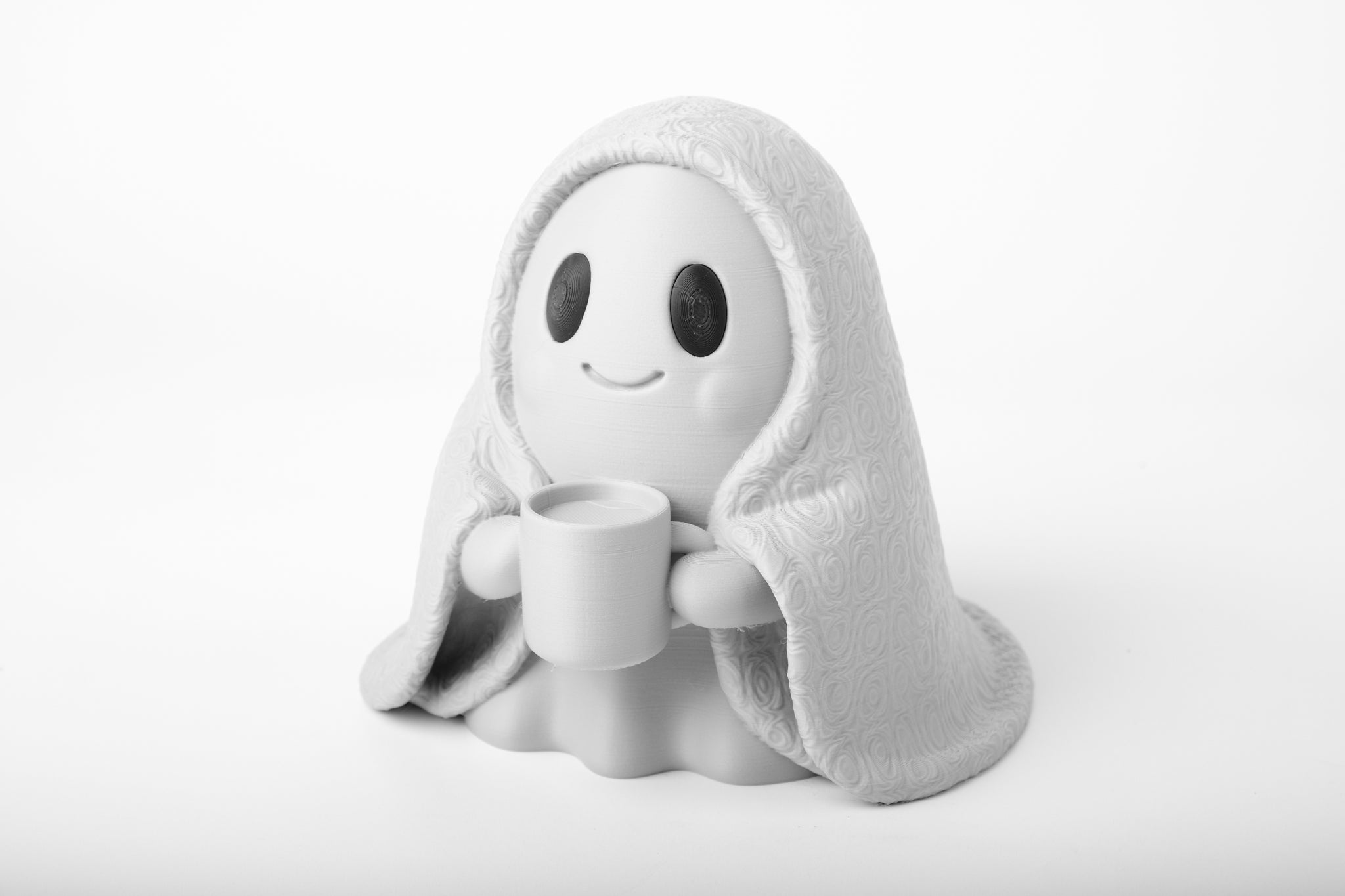 Cozy ghost figurine styled on a wooden desk beside a small plant and books, warm ambient light