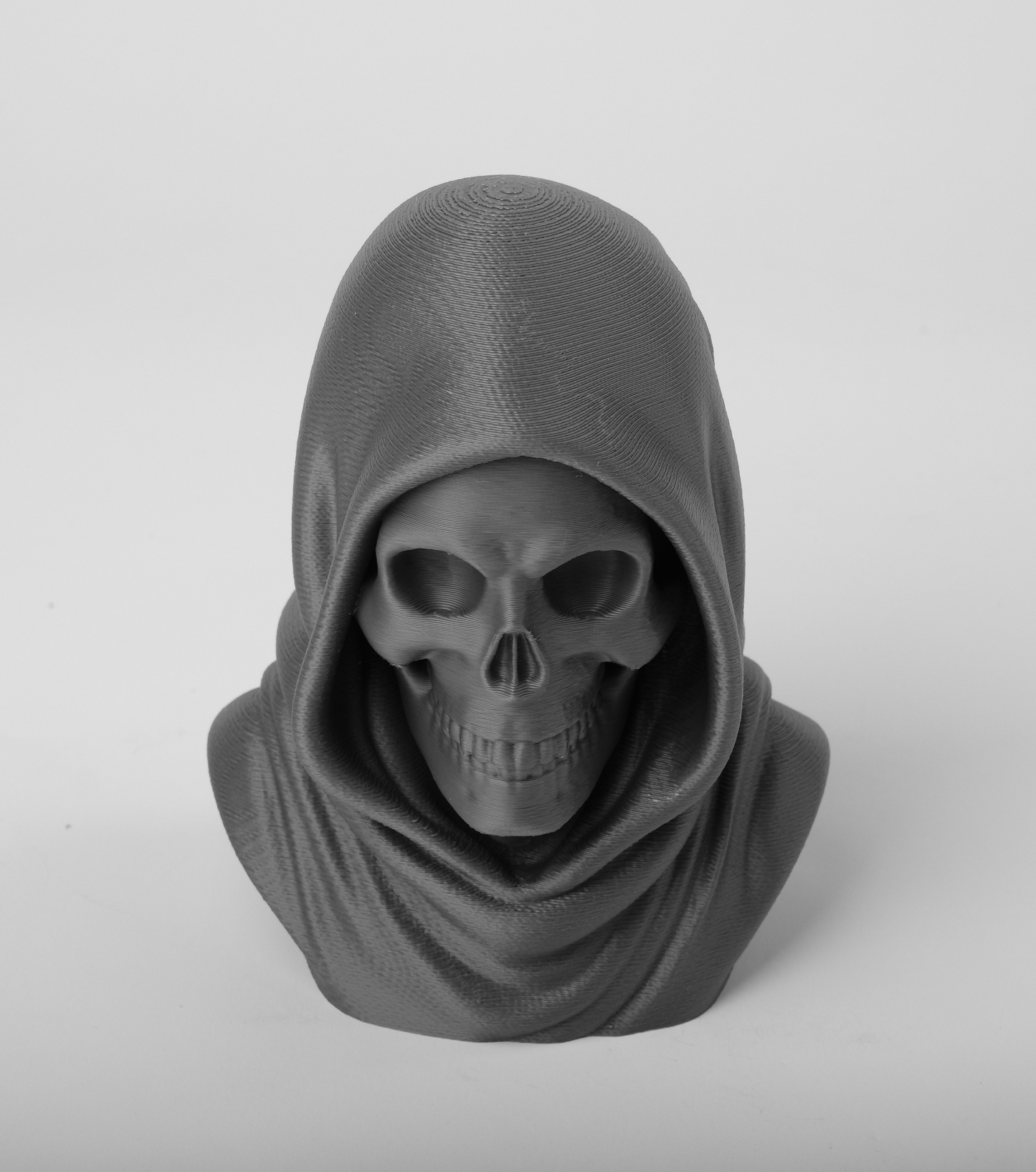 Dark gothic skull statue styled on a wooden shelf beside a black candle and dried flowers