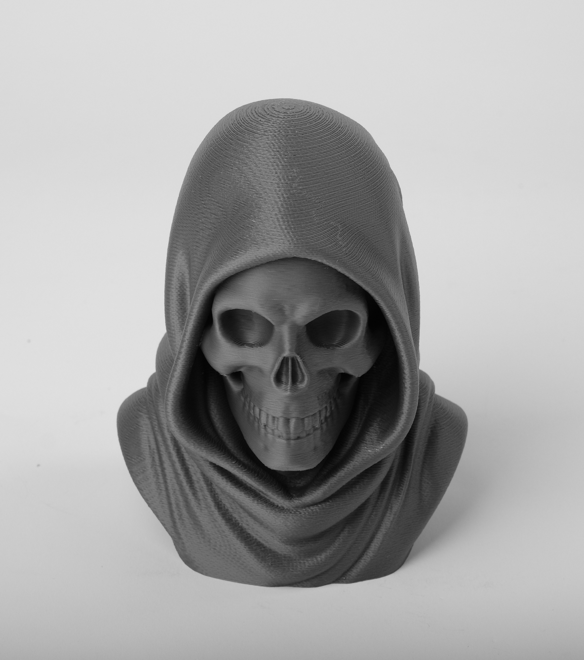 Dark gothic skull statue styled on a wooden shelf beside a black candle and dried flowers