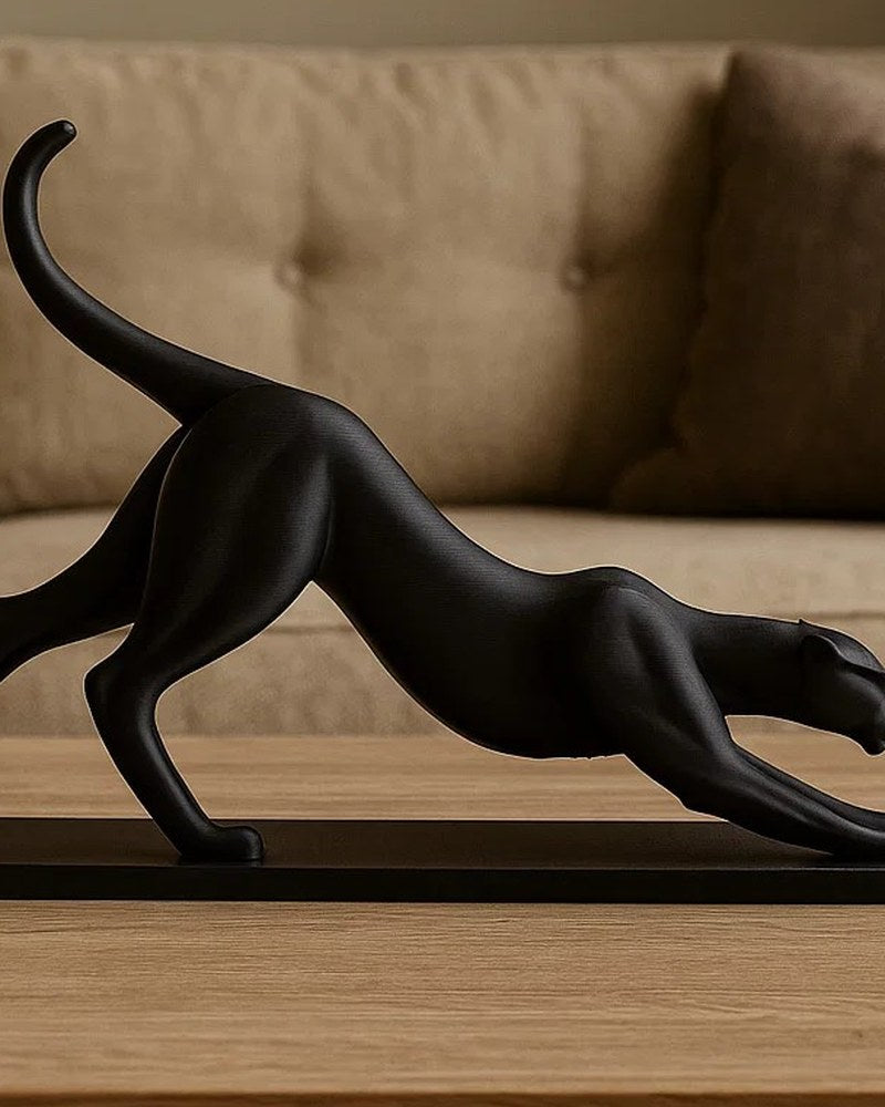 Close-up of a black panther sculpture mid-stretch on a white surface, sleek minimalist animal art