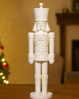 Minimalist nutcracker sculpture in matte white on a clean white shelf — front view