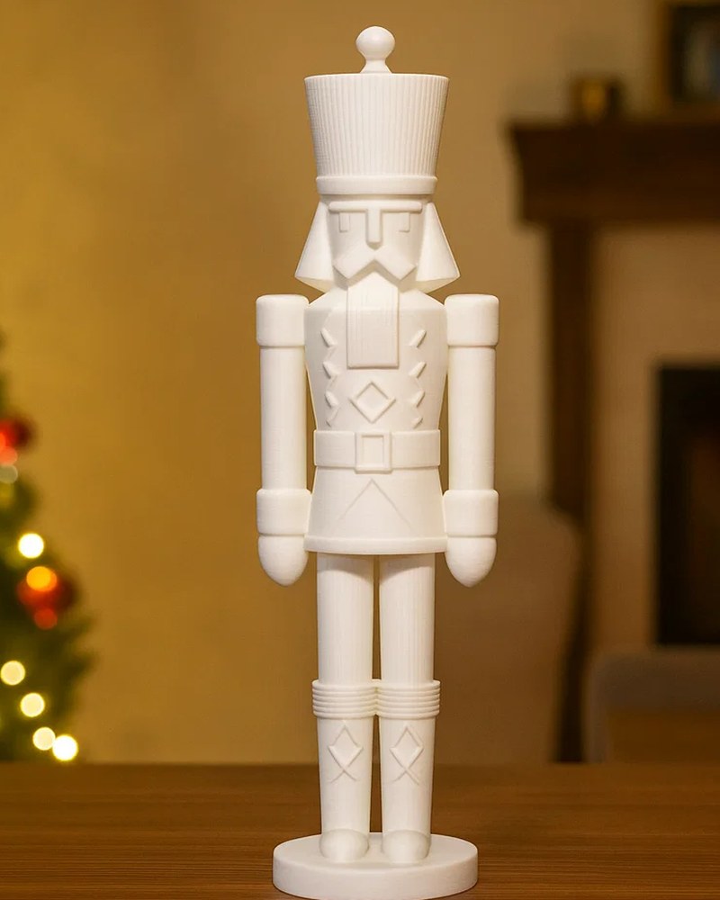 Minimalist nutcracker sculpture in matte white on a clean white shelf — front view