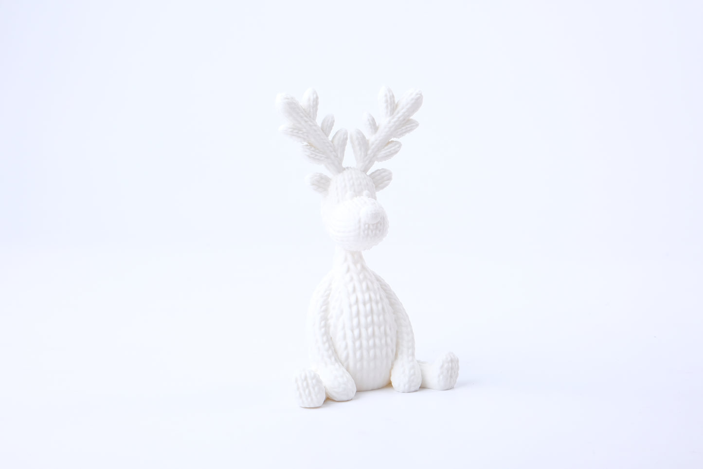 Knitted reindeer figurine styled on a shelf with candles and dried botanicals in a Scandinavian living room