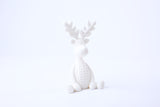 Knitted reindeer figurine styled on a shelf with candles and dried botanicals in a Scandinavian living room