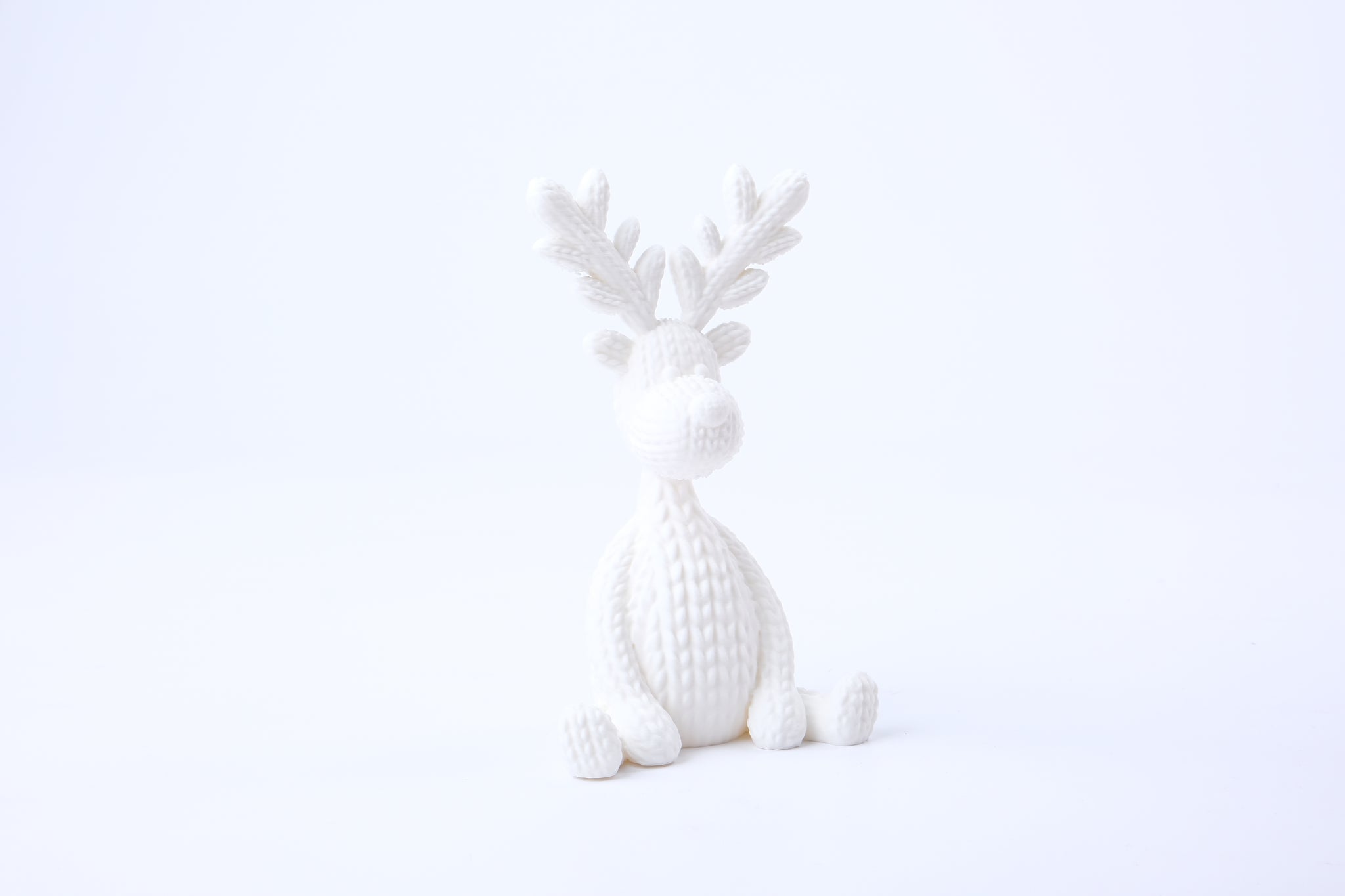 Knitted reindeer figurine styled on a shelf with candles and dried botanicals in a Scandinavian living room