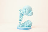Moon caretaker sculpture styled on a minimalist shelf between books and a small plant