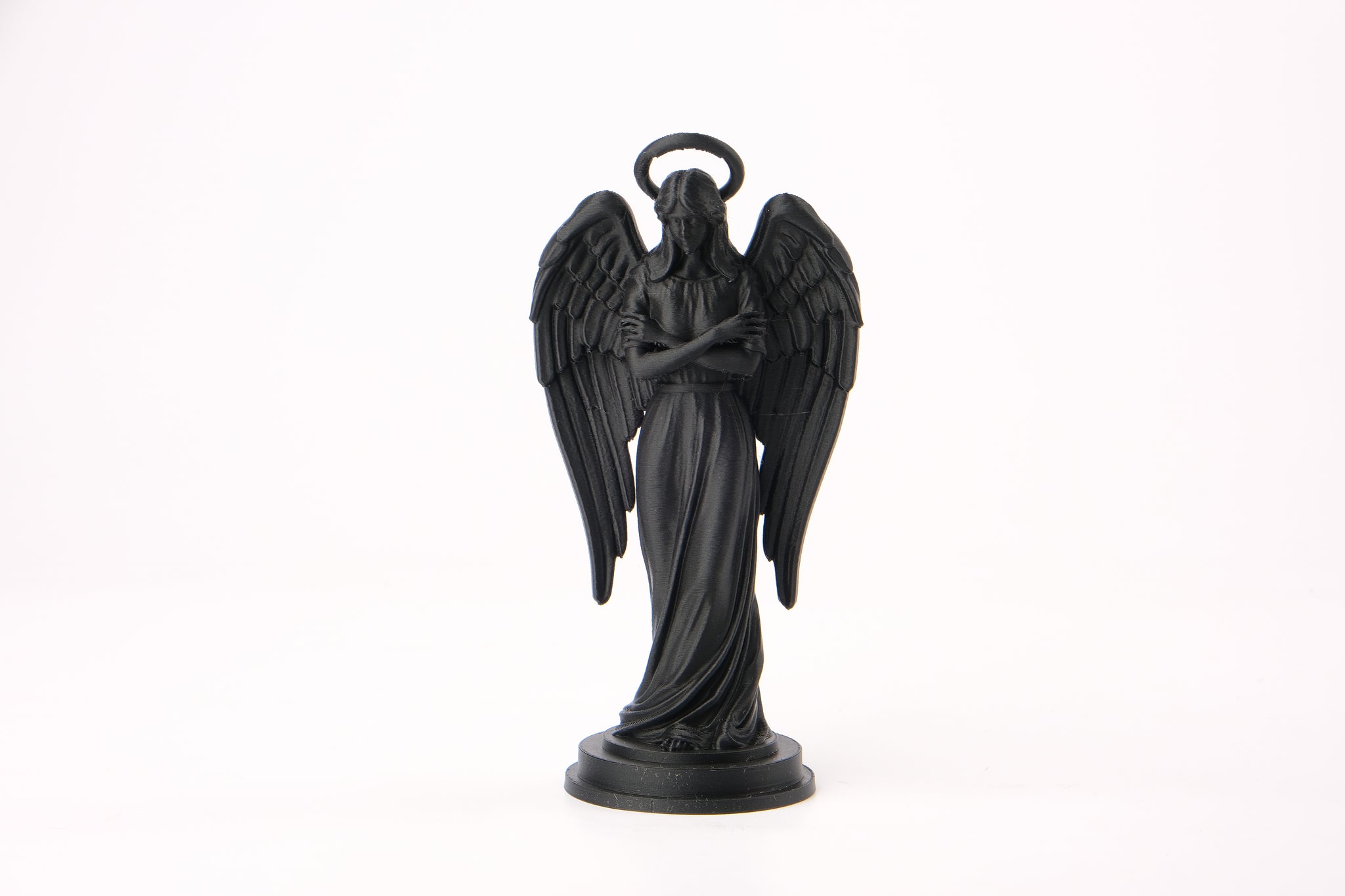 Angel figurine styled on a dark wood shelf with candles and dried botanicals