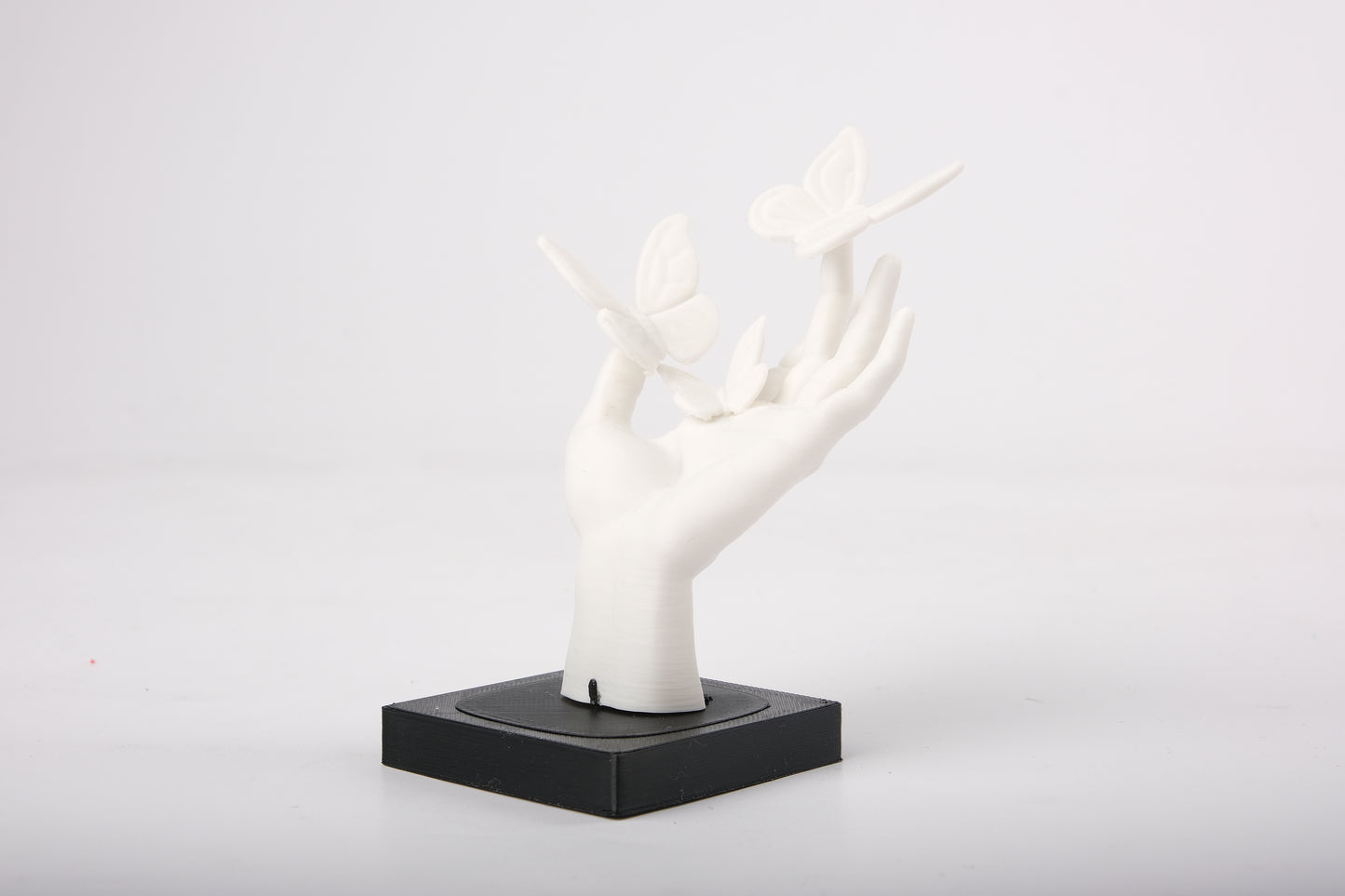 Butterfly hand sculpture styled on a minimalist wooden shelf alongside a small ceramic vase